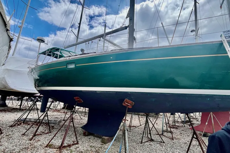 Slide: The Image of 1999 Beneteau Oceanis 381 sailboat on stands, green hull, cloudy sky background. - 22