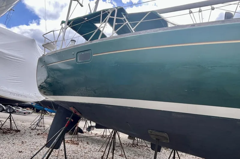 Slide: The Image of 1999 Beneteau Oceanis 381 sailboat on stands, green hull, outdoor storage. - 23