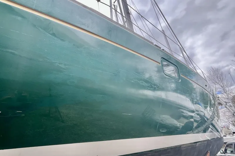 Slide: The Image of 1999 Beneteau Oceanis 381 sailboat with green hull, docked under cloudy skies. - 25