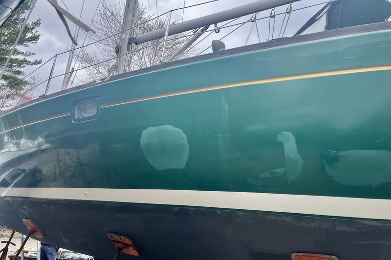 Slide: The Image of 1999 Beneteau Oceanis 381 sailboat hull with visible patches, docked outdoors. - 27