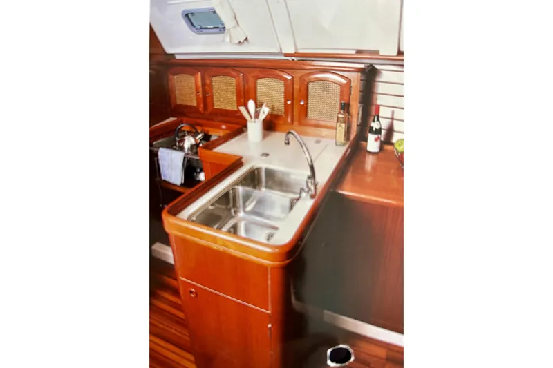 Slide: The Image of Interior of 1999 Beneteau Oceanis 381 yacht, featuring a wooden galley with sink and storage. - 3