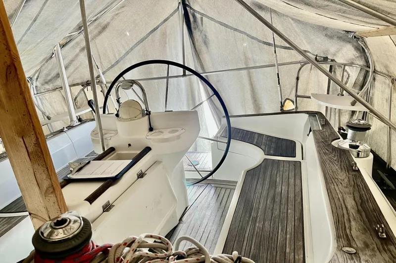 Slide: The Image of 1999 Beneteau Oceanis 381 sailboat cockpit under cover, featuring wooden deck and steering wheel. - 5