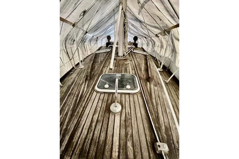 Slide: The Image of 1999 Beneteau Oceanis 381 sailboat deck under protective cover, showcasing wooden finish and hatch. - 7
