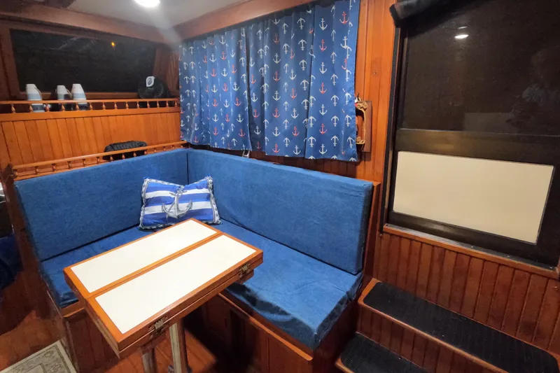 Slide: The Image of Cozy 1986 CHB Senator boat interior with blue seating and nautical-themed curtains. - 51