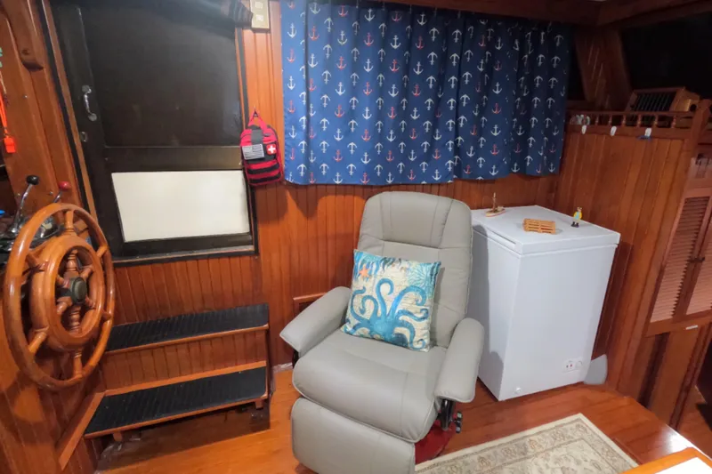 Slide: The Image of 1986 CHB Senator boat interior with nautical decor, featuring a captain's chair and wooden helm. - 55