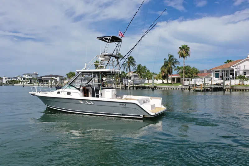 The Image of 1992 Luhrs 300 Tournament boat on water, with fishing rods, near waterfront homes. - 0