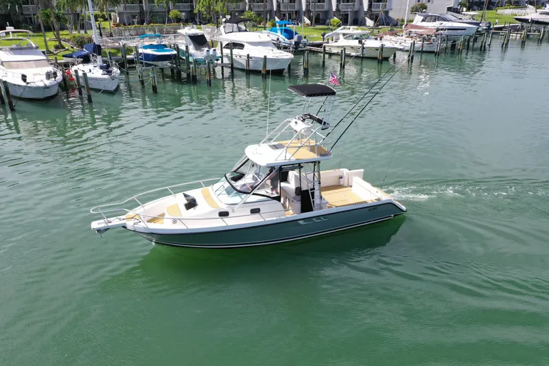 Slide: The Image of 1992 Luhrs 300 Tournament boat cruising in a marina with docked vessels nearby. - 1