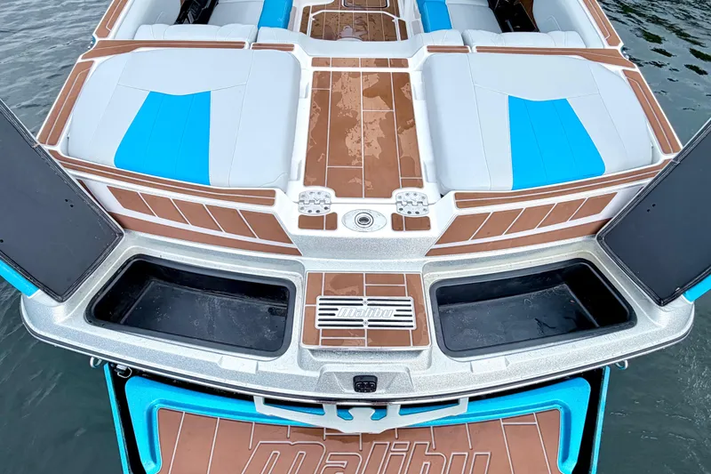 Slide: The Image of 2023 Malibu Wakesetter 23 MXZ boat interior with blue and white seating on water. - 25