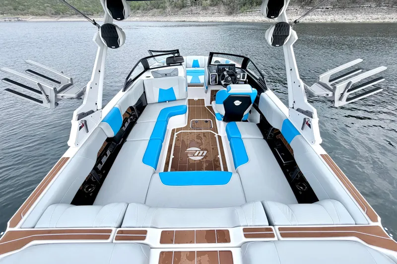 Slide: The Image of 2023 Malibu Wakesetter 23 MXZ boat interior with blue and white seating on a lake. - 29