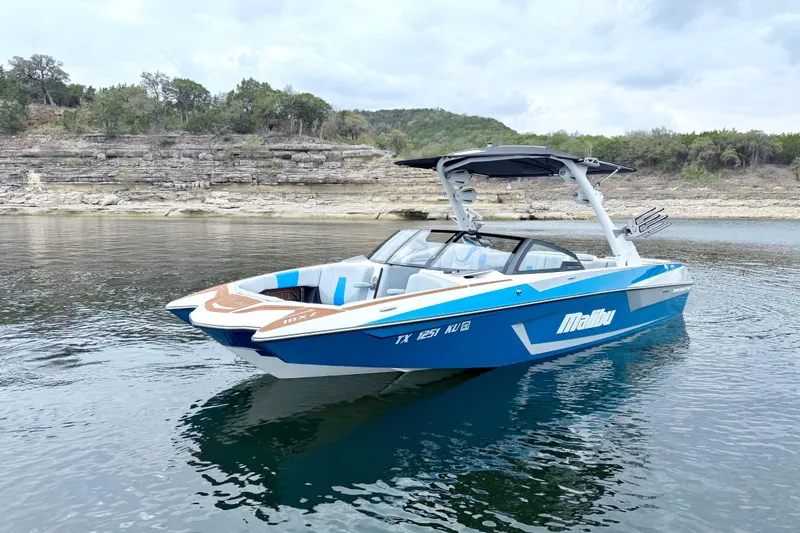 Slide: The Image of 2023 Malibu Wakesetter 23 MXZ boat on calm lake with rocky shoreline. - 3