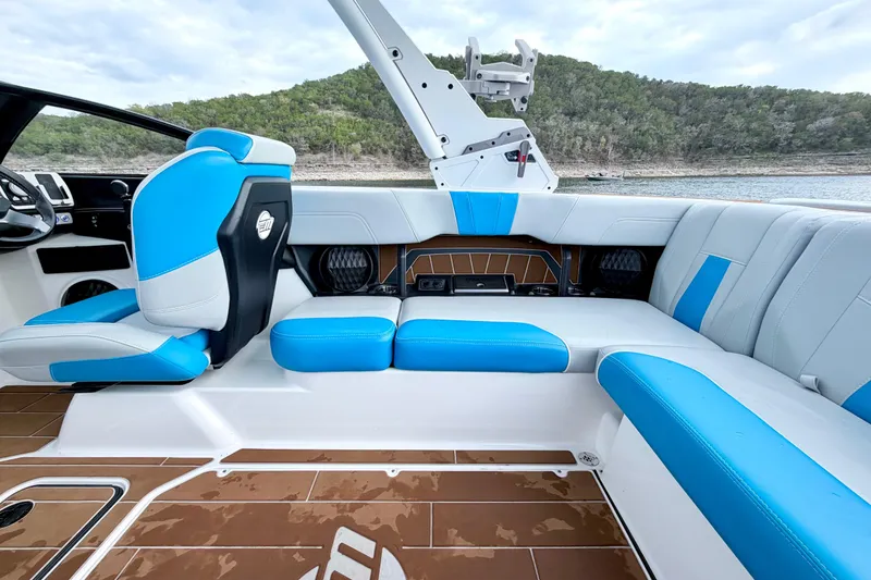 Slide: The Image of 2023 Malibu Wakesetter 23 MXZ interior with blue and white seating, lake view background. - 34