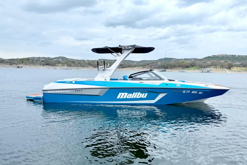 Slide: The Image of 2023 Malibu Wakesetter 23 MXZ boat on a calm lake under cloudy skies. - 4