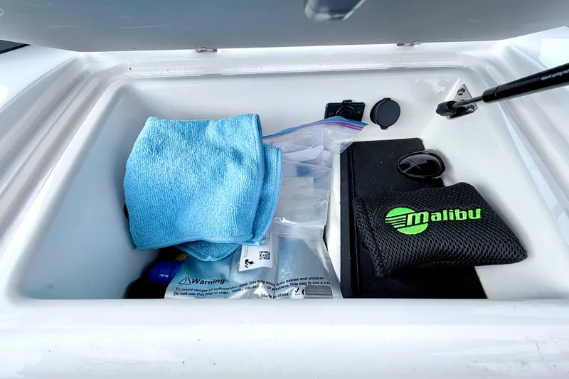 Slide: The Image of Storage compartment in 2023 Malibu Wakesetter 23 MXZ with accessories and cleaning cloth. - 40