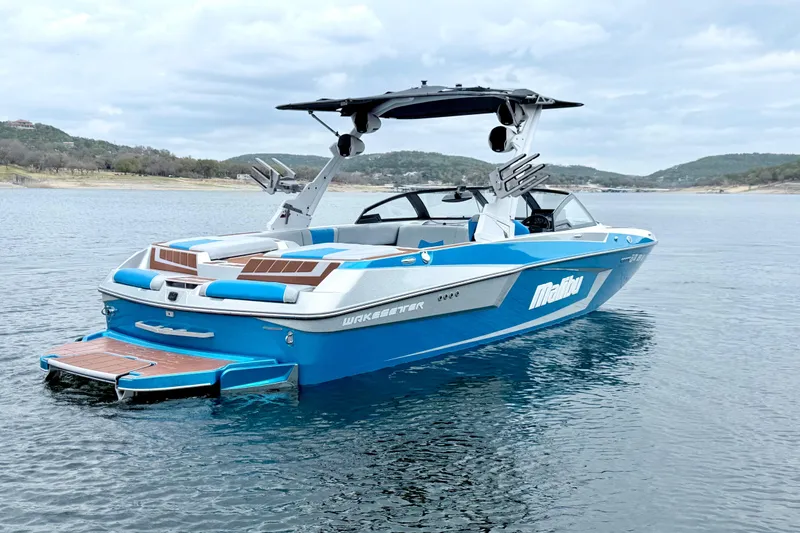 Slide: The Image of 2023 Malibu Wakesetter 23 MXZ boat on a serene lake with scenic hills. - 5