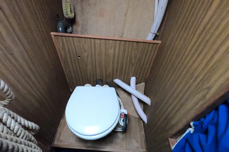 Slide: The Image of 1972 Morgan 27 boat interior with compact marine toilet and wooden paneling. - 15