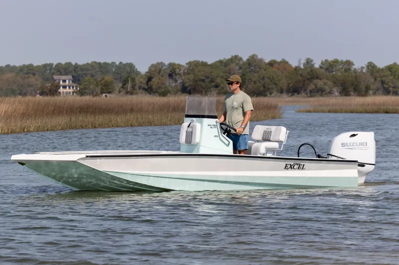 The Image of 2026 Excel 203 Bay Pro Elite boat cruising on a calm river with a Suzuki engine. - 0