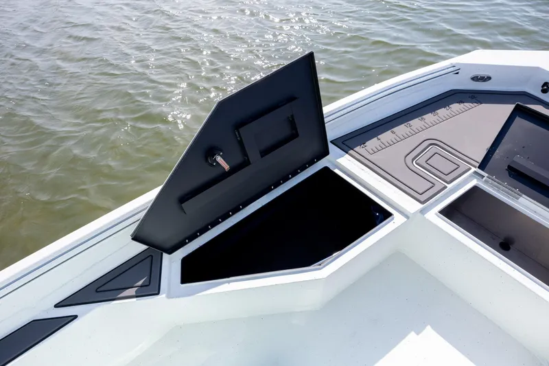 Slide: The Image of 2026 Excel 203 Bay Pro Elite boat with open storage compartment on calm water. - 13