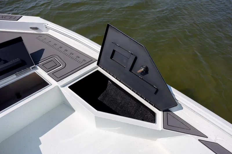 Slide: The Image of 2026 Excel 203 Bay Pro Elite boat with open storage compartments on calm water. - 14