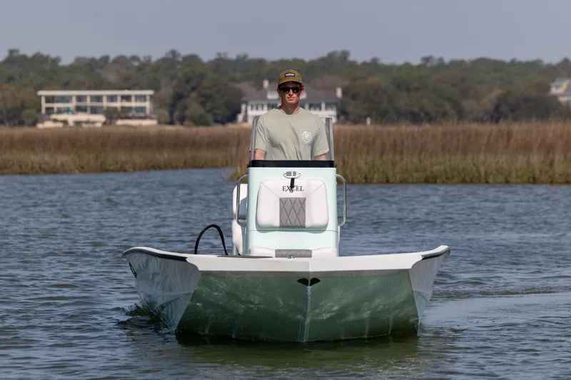 Slide: The Image of 2026 Excel 203 Bay Pro Elite boat on water with driver, scenic background. - 2