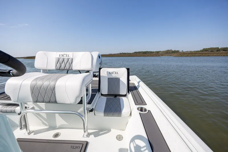 Slide: The Image of 2026 Excel 203 Bay Pro Elite boat interior with cushioned seating on calm water. - 25