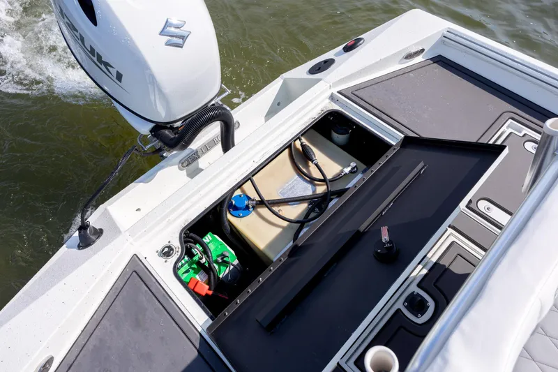Slide: The Image of 2026 Excel 203 Bay Pro Elite boat with open storage compartment and Suzuki motor. - 27
