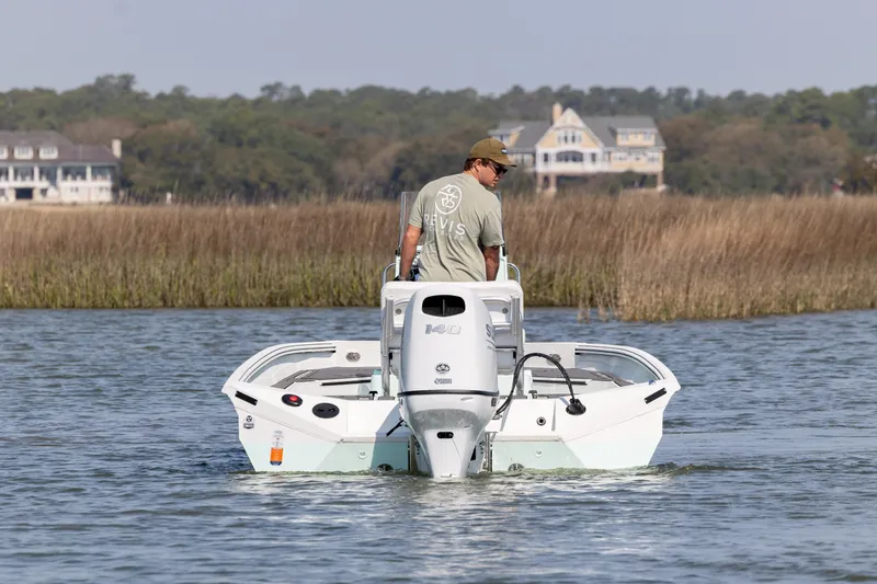 Slide: The Image of Man steering 2026 Excel 203 Bay Pro Elite boat on calm water near marshland. - 6