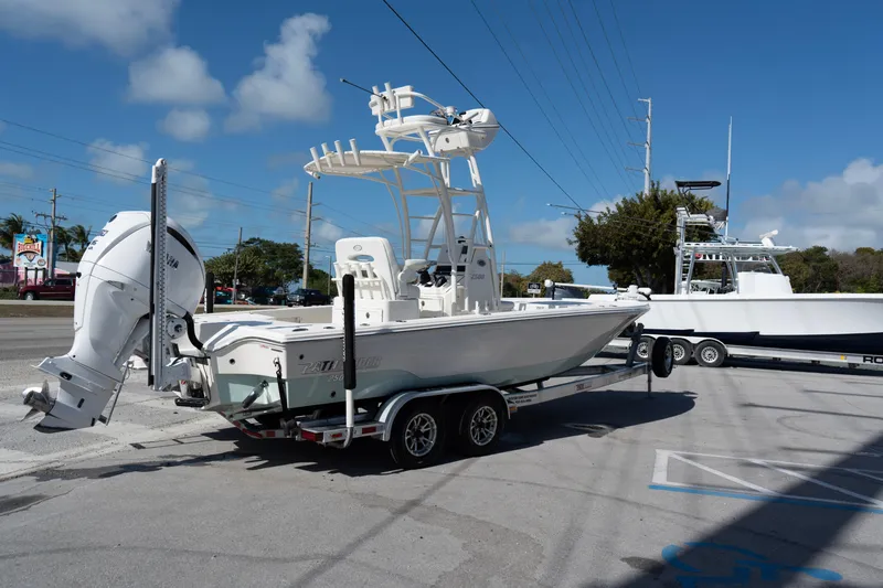 Slide: The Image of 2023 Pathfinder 2500 Hybrid boat on trailer, parked outdoors under clear blue sky. - 2