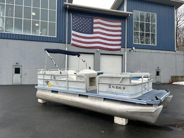 The Image of 1998 Palm Beach 200 pontoon boat in front of building with US flag. - 1