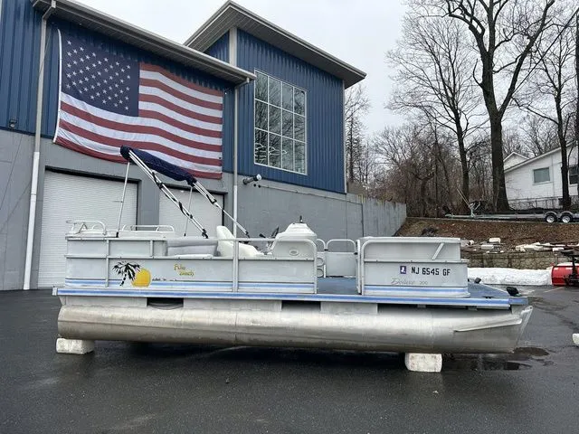 Slide: The Image of 1998 Palm Beach 200 pontoon boat in front of building with US flag. - 3
