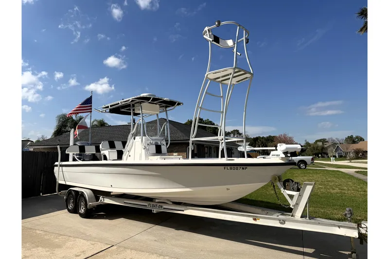 The Image of 2012 Edgewater 240 Inshore boat on trailer, American flag, clear sky background. - 0