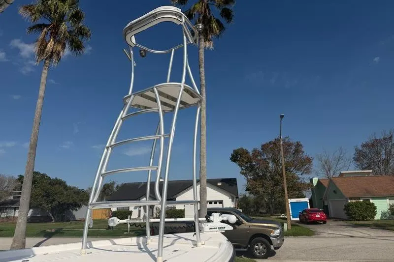 Slide: The Image of 2012 Edgewater 240 Inshore boat with a tall observation tower, parked in a residential area. - 2