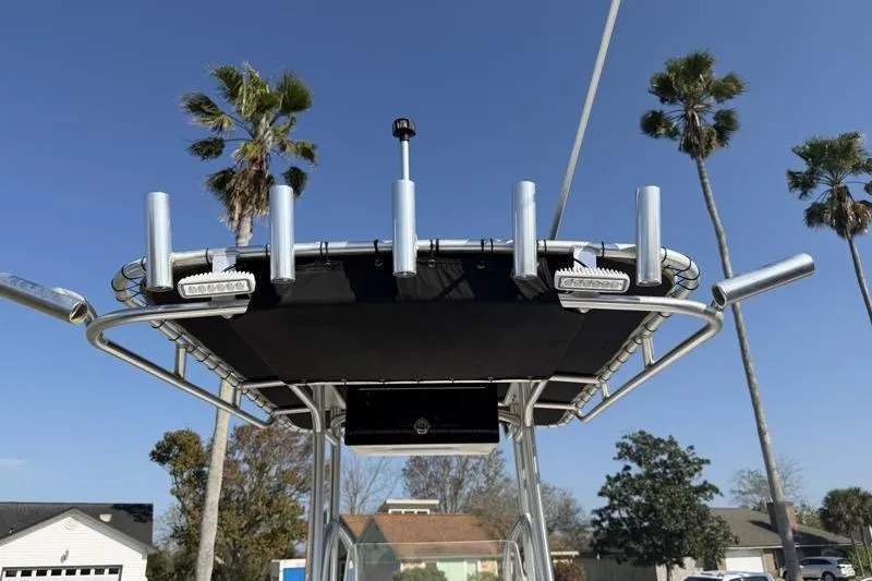 Slide: The Image of 2012 Edgewater 240 Inshore boat with T-top and rod holders, palm trees in background. - 70