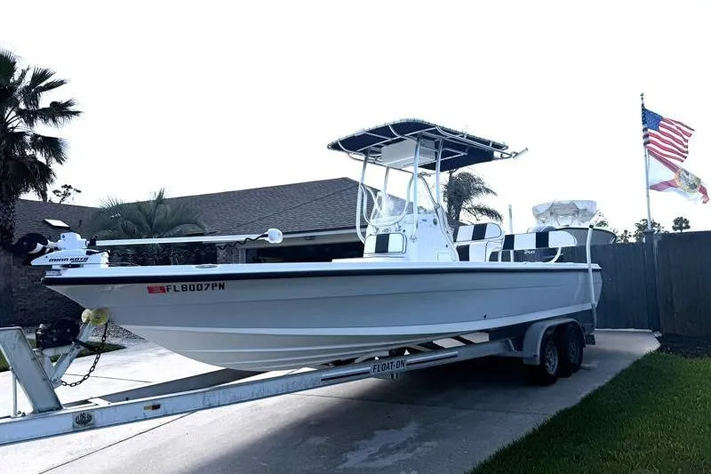 Slide: The Image of 2012 Edgewater 240 Inshore boat on trailer, parked in driveway with American flag. - 8