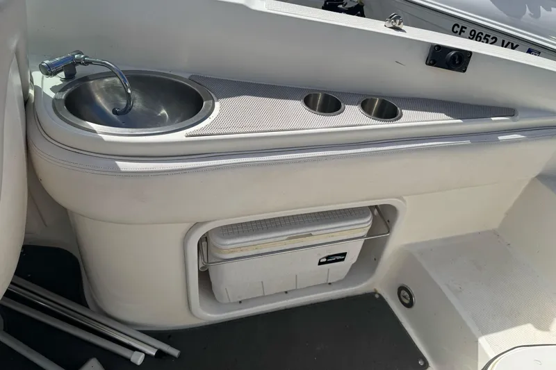 Slide: The Image of 2012 Sea Ray 240 Sundeck interior with sink, cup holders, and storage compartment. - 10