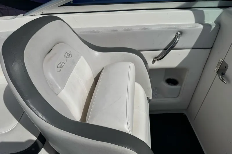 Slide: The Image of Captain's seat on a 2012 Sea Ray 240 Sundeck boat, featuring white and gray upholstery. - 11