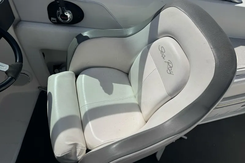 Slide: The Image of Captain's seat of 2012 Sea Ray 240 Sundeck boat, featuring white and gray upholstery. - 13