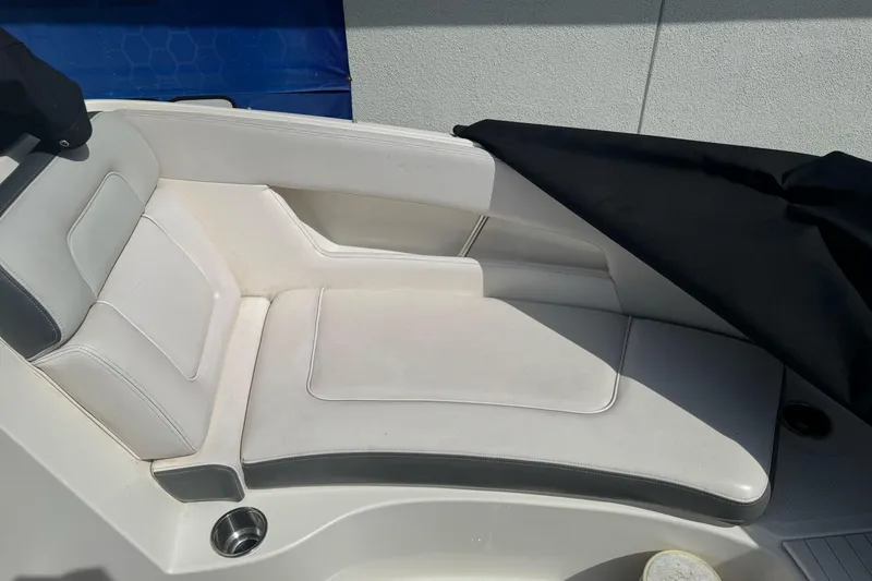 Slide: The Image of 2012 Sea Ray 240 Sundeck boat seating area with white upholstery and cup holder. - 20