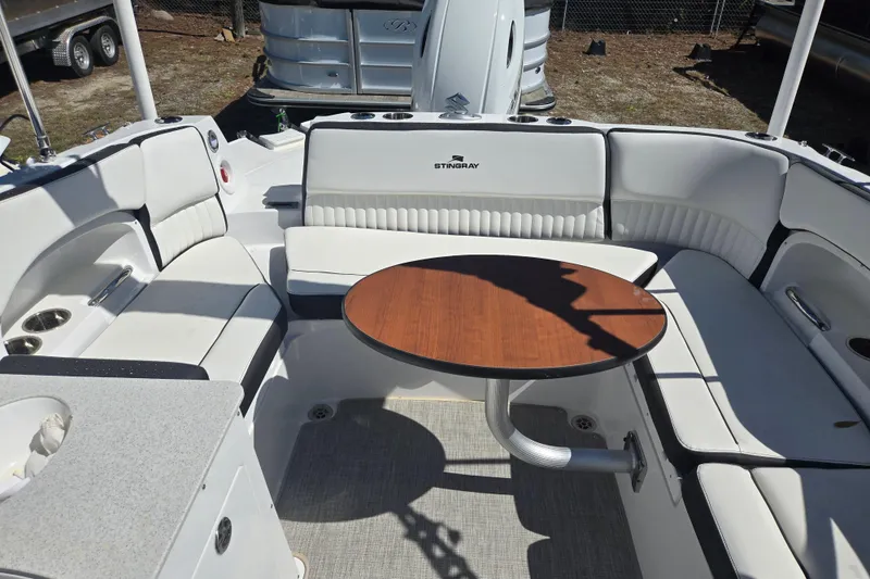 Slide: The Image of 2026 Stingray 231 DC boat interior with white seating and wooden table. - 12