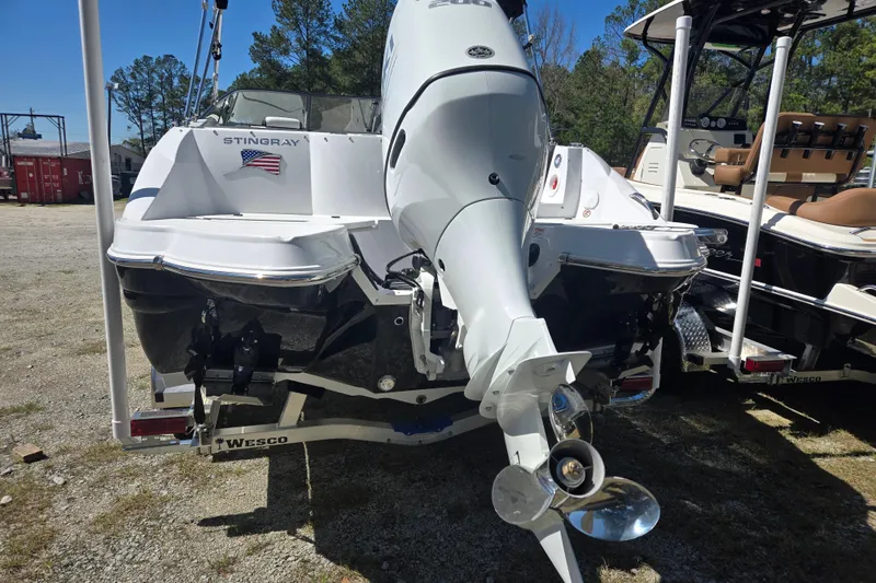 Slide: The Image of 2026 Stingray 231 DC boat with outboard motor, parked on a trailer. - 2