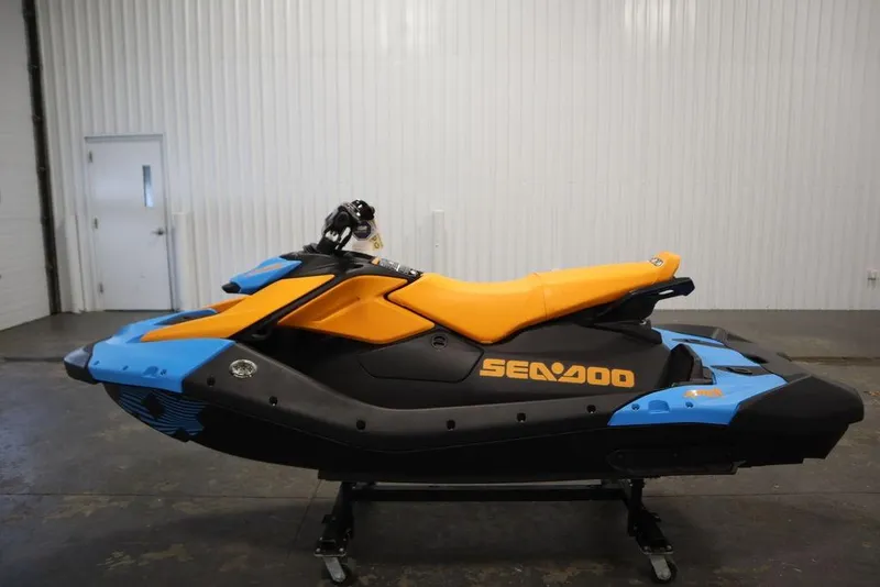 Slide: The Image of 2026 Sea-Doo Spark Trixx for 3, vibrant orange and blue design, in a showroom. - 8