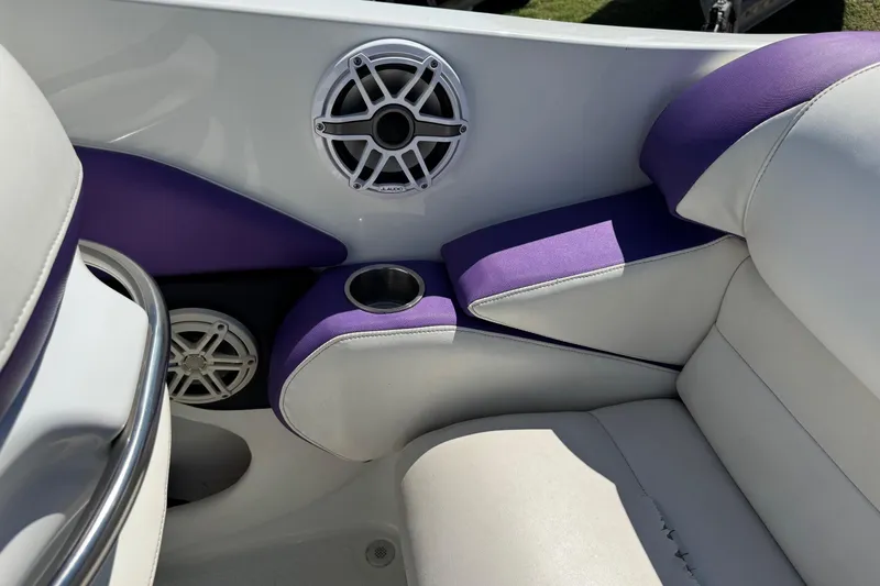 Slide: The Image of Interior of 1999 Baja 25 Outlaw boat with purple and white seating, speakers, and cup holder. - 10