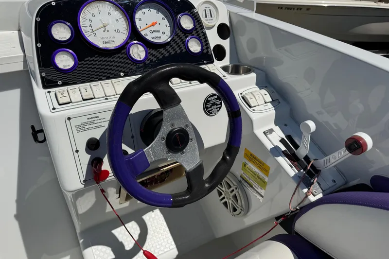 Slide: The Image of 1999 Baja 25 Outlaw boat dashboard with steering wheel and gauges. - 11