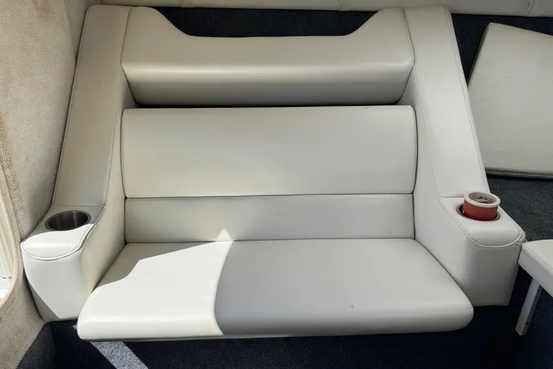 Slide: The Image of 1999 Baja 25 Outlaw boat interior with white cushioned seating and cup holders. - 23