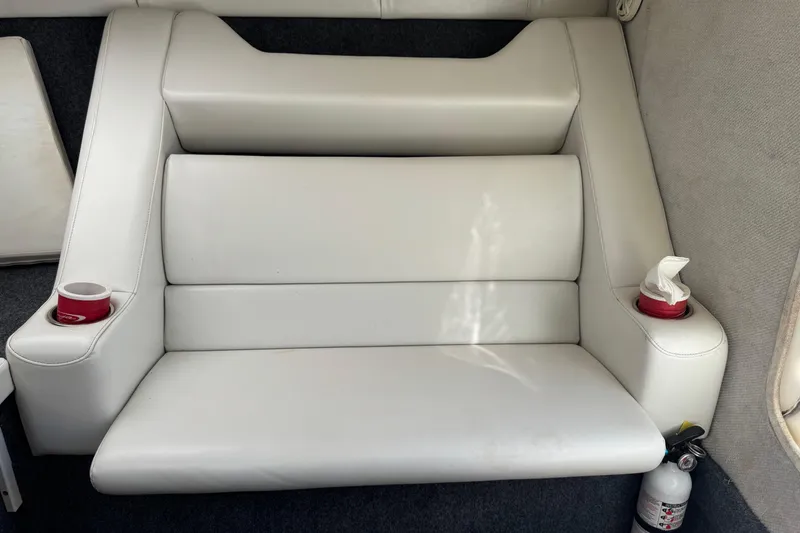 Slide: The Image of White leather seating in a 1999 Baja 25 Outlaw boat with cup holders and fire extinguisher. - 24