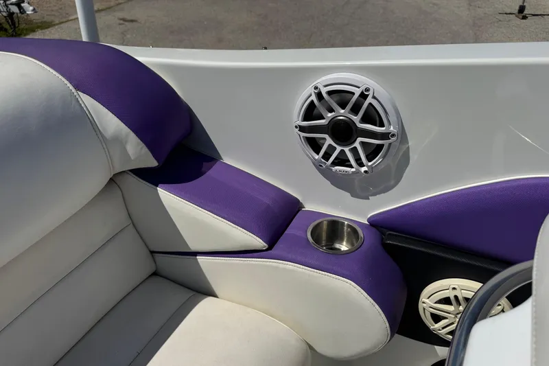 Slide: The Image of 1999 Baja 25 Outlaw boat interior with purple and white seating, speaker, and cup holder. - 9