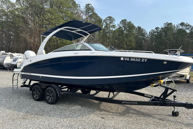 The Image of 2023 Four Winns HD8 OB boat on trailer, parked outdoors with trees in background. - 1