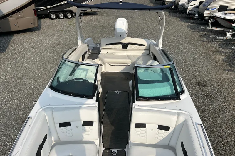 Slide: The Image of 2023 Four Winns HD8 OB boat with open deck and seating, parked on gravel. - 17