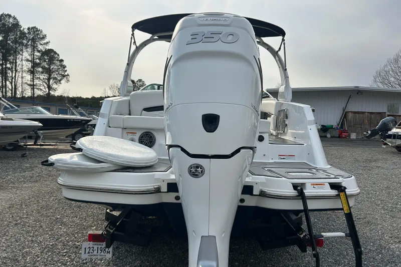 Slide: The Image of 2023 Four Winns HD8 OB boat with powerful outboard motor, parked on gravel lot. - 3