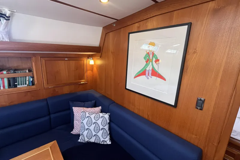 Slide: The Image of Cozy Rustler 37 yacht interior with blue seating, wooden paneling, and framed artwork. - 20