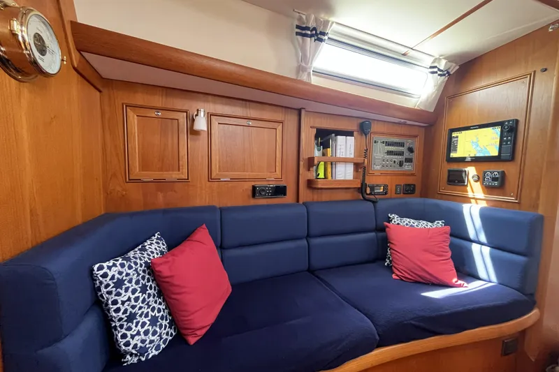 Slide: The Image of Interior of 2017 Rustler 37 yacht with blue seating, red pillows, and navigation equipment. - 24